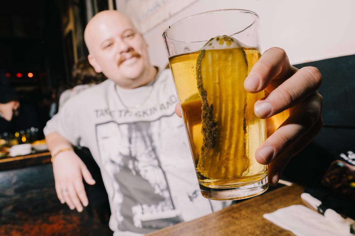 Joshua Margherita, of St. Louis’ The Grove neighborhood, shows off his Stag and a pickle during a funeral for the beer being served on tap at The Crow’s Nest on Friday, Feb. 27, 2026, in Maplewood. Margherita said he learned of the delicacy during his time at the University of Missouri.