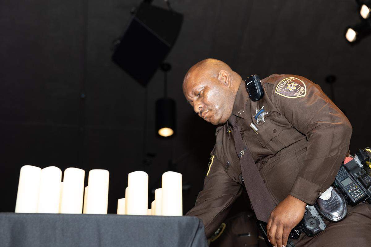 Deputy Chris Davis places one amongst many candles during a memorial service for fallen police officers of St. Clair County in Christ Church on Frank Scott Parkway in Fairview Heights, Ill. on May 7, 2024.