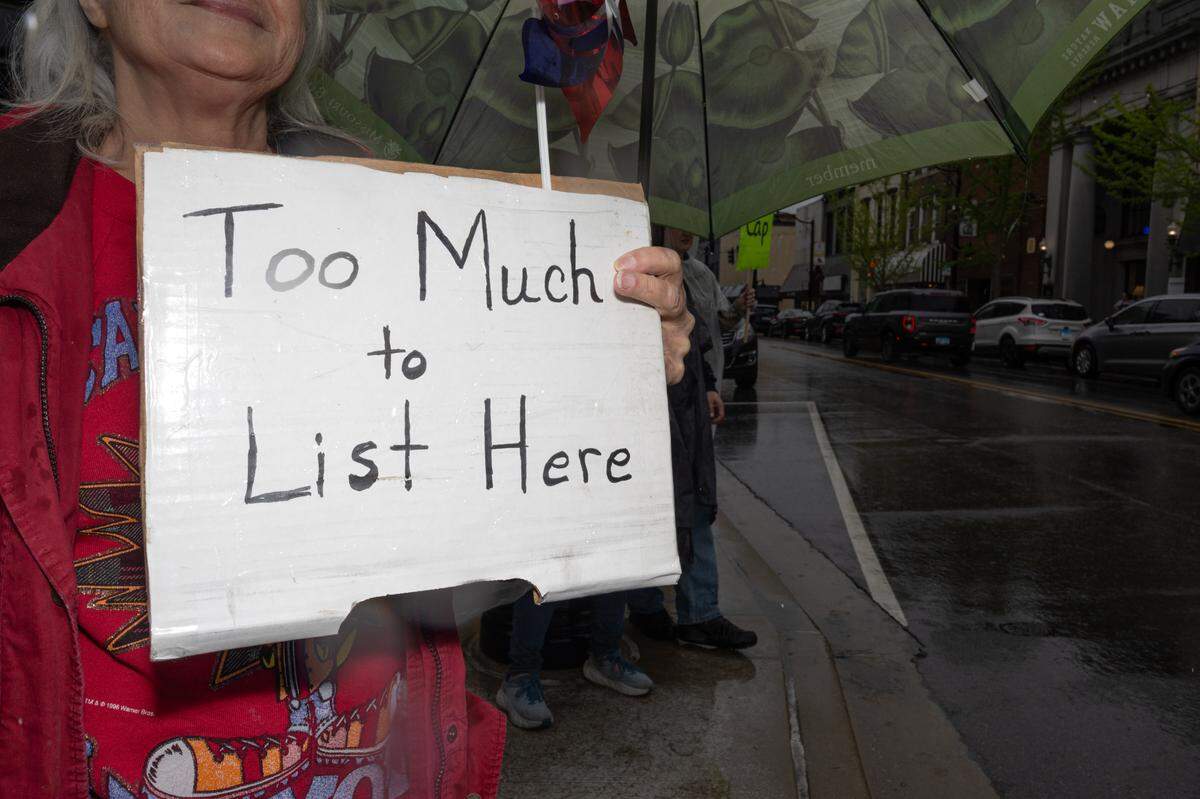 A protestor holds up a sign saying “Too Much to List Here” during Saturday’s protest at Belleville’s Public Square.