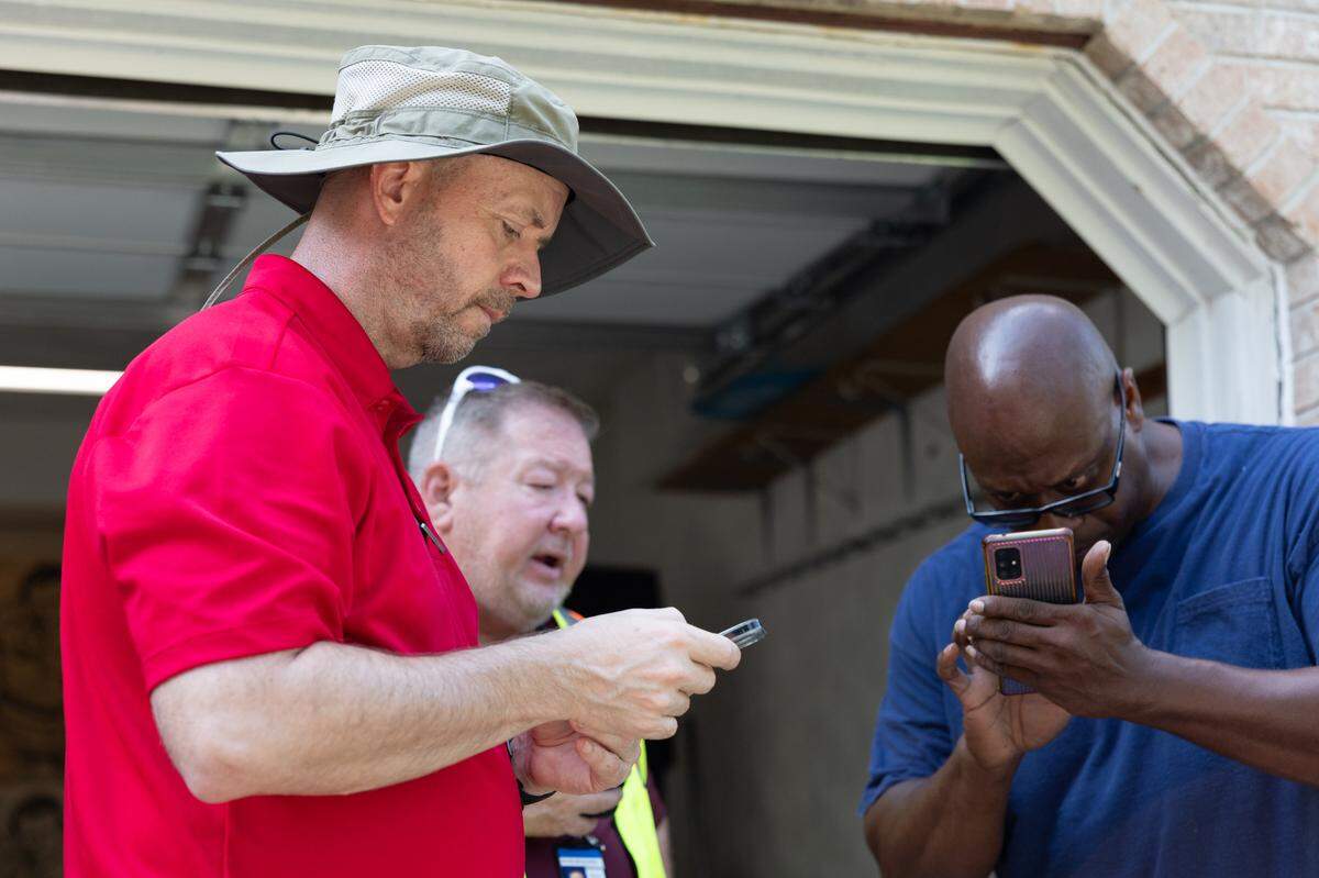 Bryan Whitaker of Belleville (blue) shows photos of the damage of his house caused by heavy flooding earlier that week.