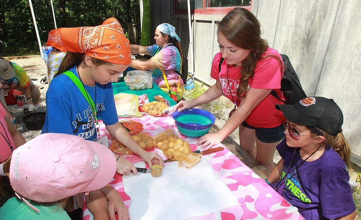 In this file photo, intern Casey Koertge, 22, top right, helps campers prepare lunch at Camp Torqua in rural Edwardsville in 2014. The camp is owned by Girl Scouts of Southern Illinois.