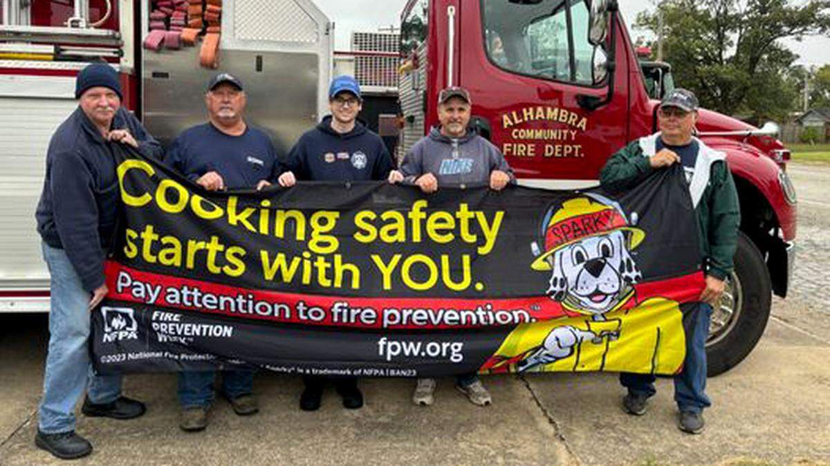 Chief Randy Take, Alan Daiber, Andrew Otrembiak, Bob Frank and Gary Boda show off the banner donated by State Farm in honor of Fire Prevention Month.
