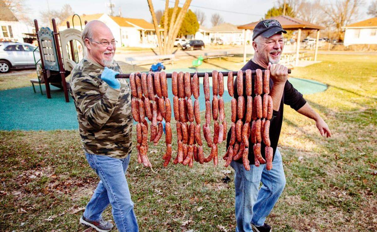 Juan Mena, 63, of Fairmont City, and Frank Gavlick, 62, of Collinsville, carry chorizo links out to a smoker on Dec. 23, in Fairmont City.