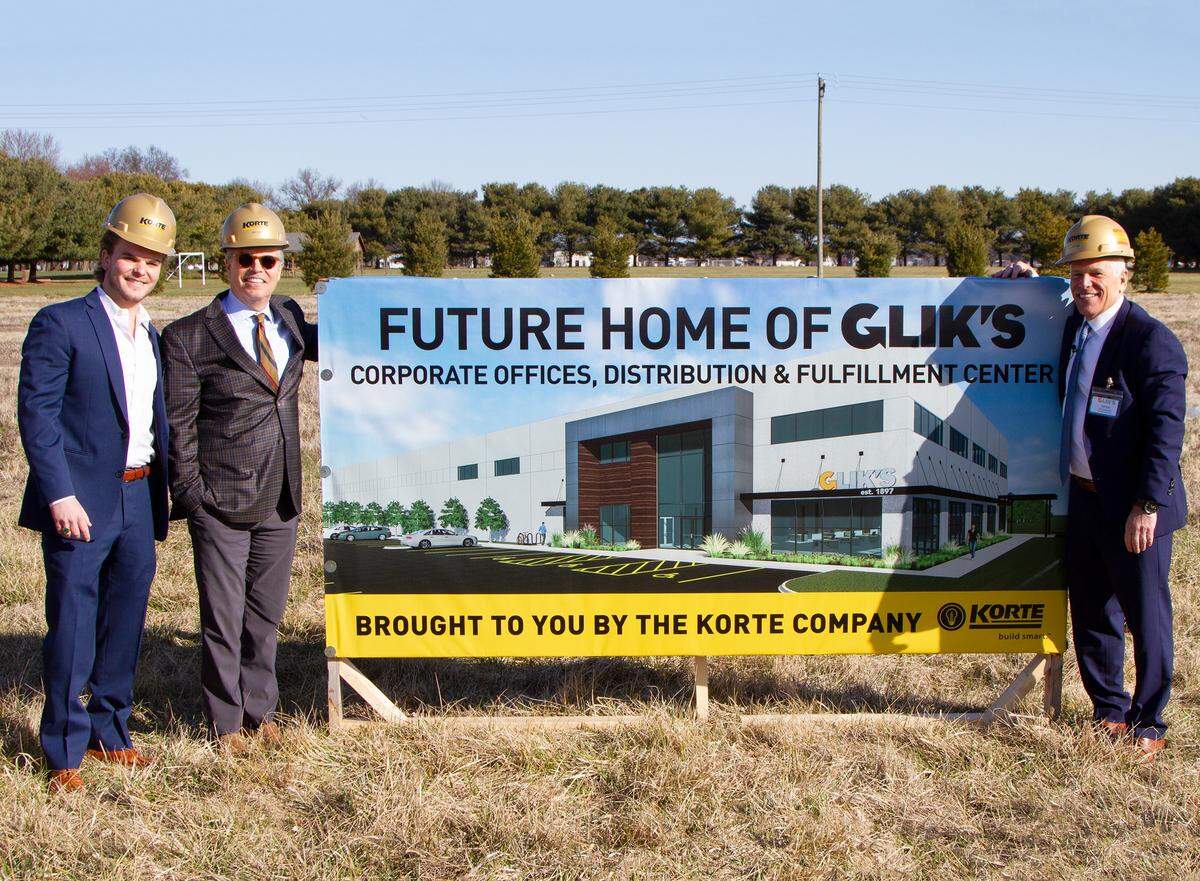 Elliot, Jim and Jeff Glik pose next to a sign at the Collinsville groundbreaking for a new building that will house corporate offices and a distribution and fulfillment center for Glik’s department stores.