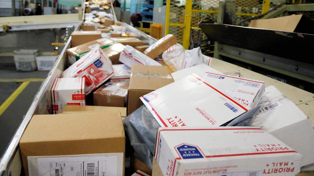 Packages with federal income tax returns are sorted on the night of the tax deadline in this 2019 file photo.