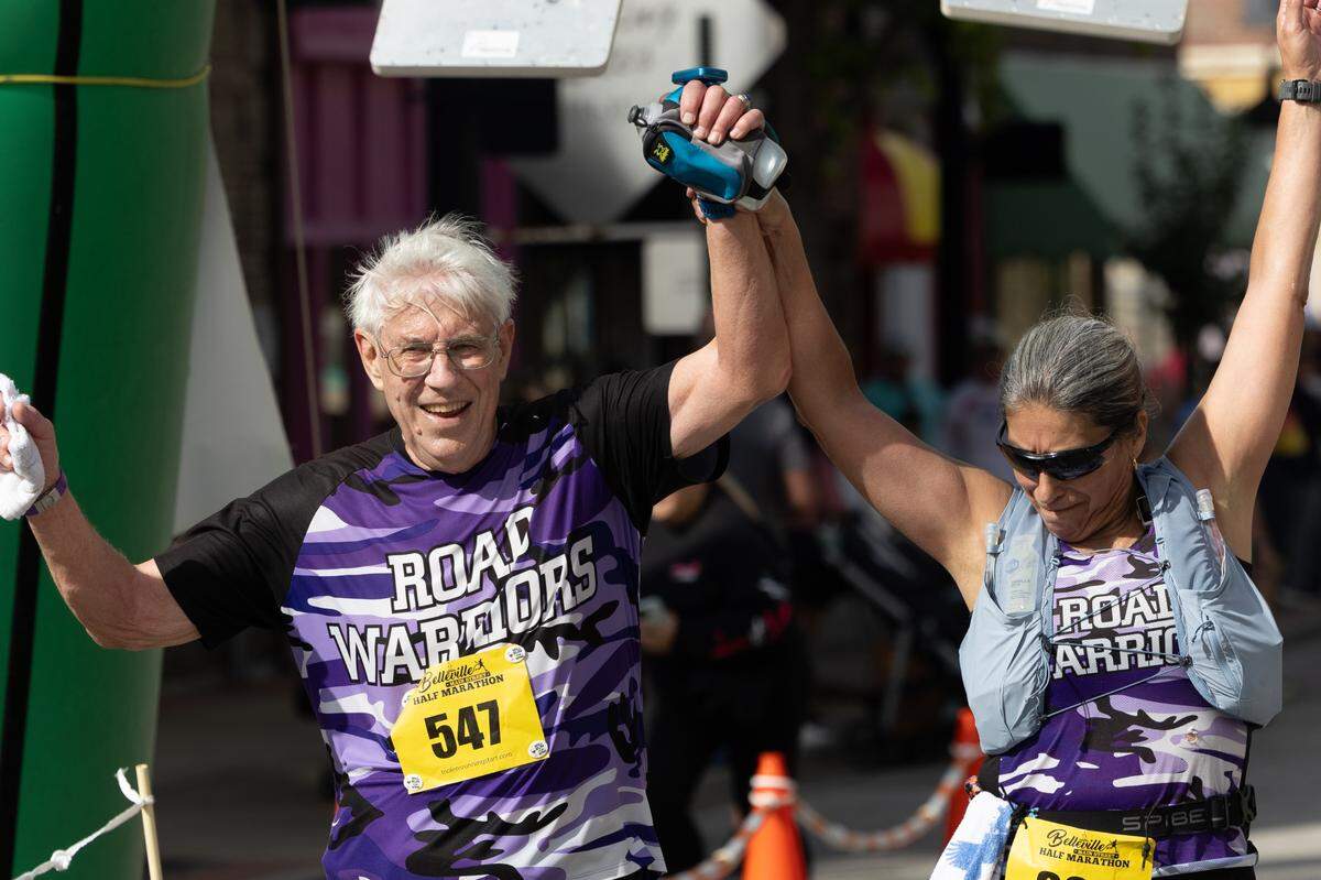A couple holds up their hands in triumph after finishing a half-marathon at the Belleville Marathon on Sept. 28, 2024.