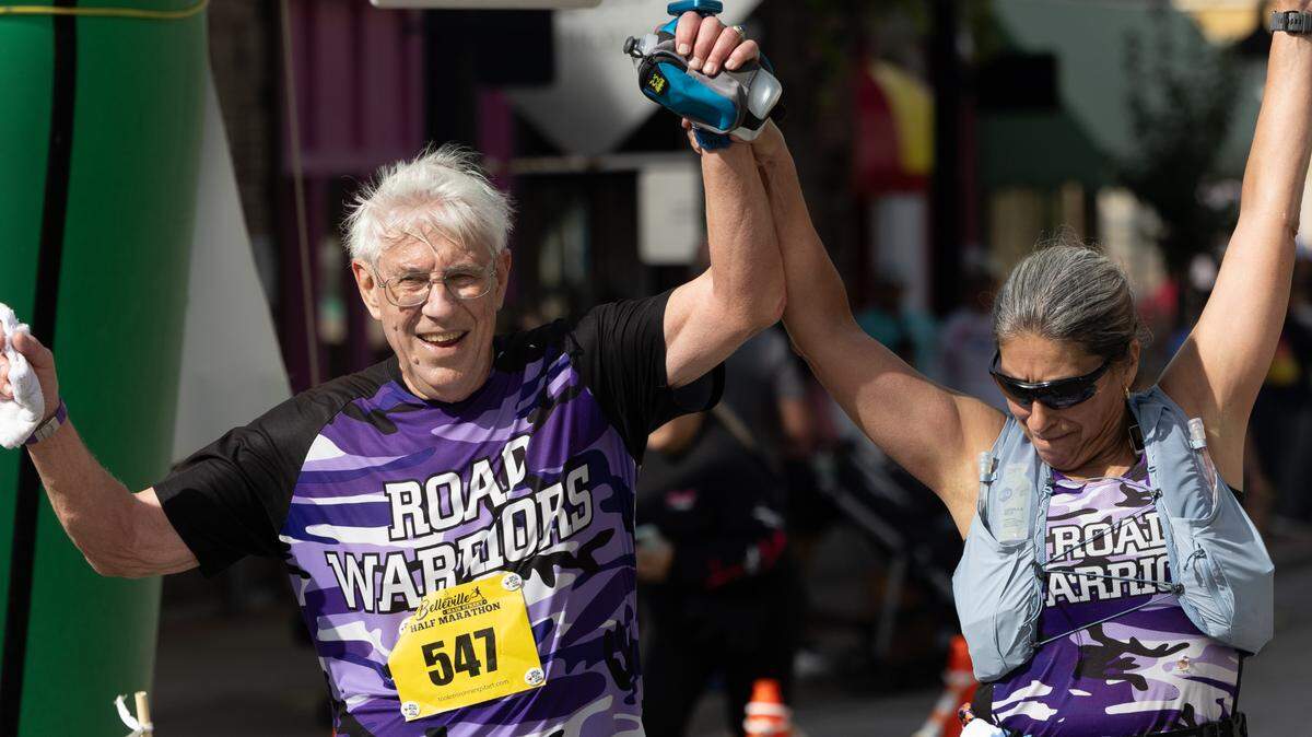 A couple holds up their hands in triumph after finishing a half-marathon at the Belleville Main Street Marathon on Sept. 28, 2024.