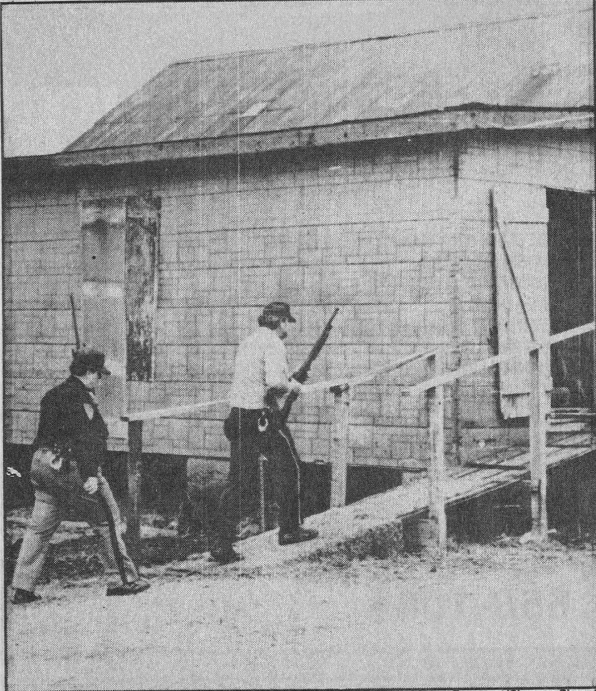 Armed authorities check an abandoned building in East Carondelet for the big black cat in December 1986.
