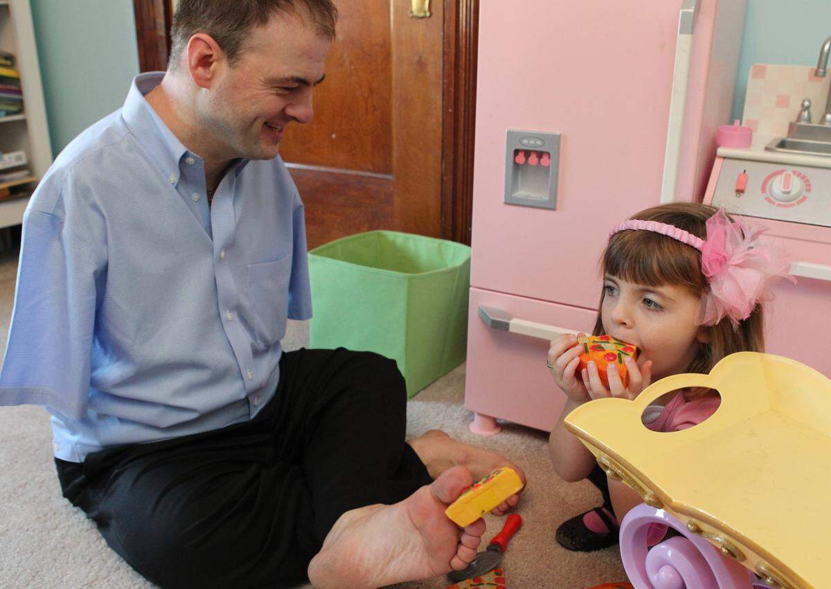 Faith Foppe, 4, pretends to eat pizza made of construction paper as her father, John, watches with amusement.