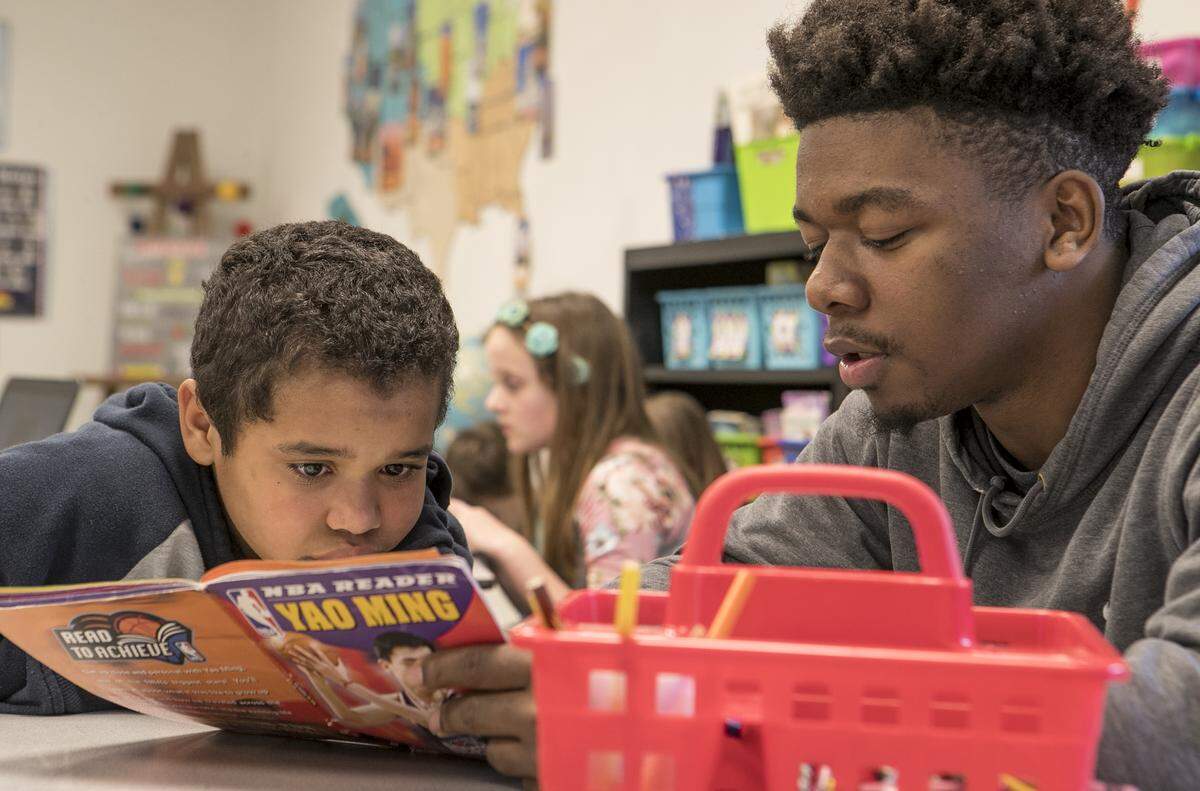 Fourth grade student Jordyn White and Sparta High School senior Jonathan Williams read a book about NBA player Yao Ming. Sparta High School students work with elementary students to gain work experience and see if they might enjoy a teaching career.