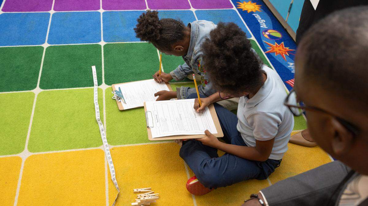 Fedrick Ingram, secretary treasurer for the American Federation of Teachers, watches on as children perform math exercises at James Avant Elementary in Washington Park, Ill. on Oct. 8, 2024.