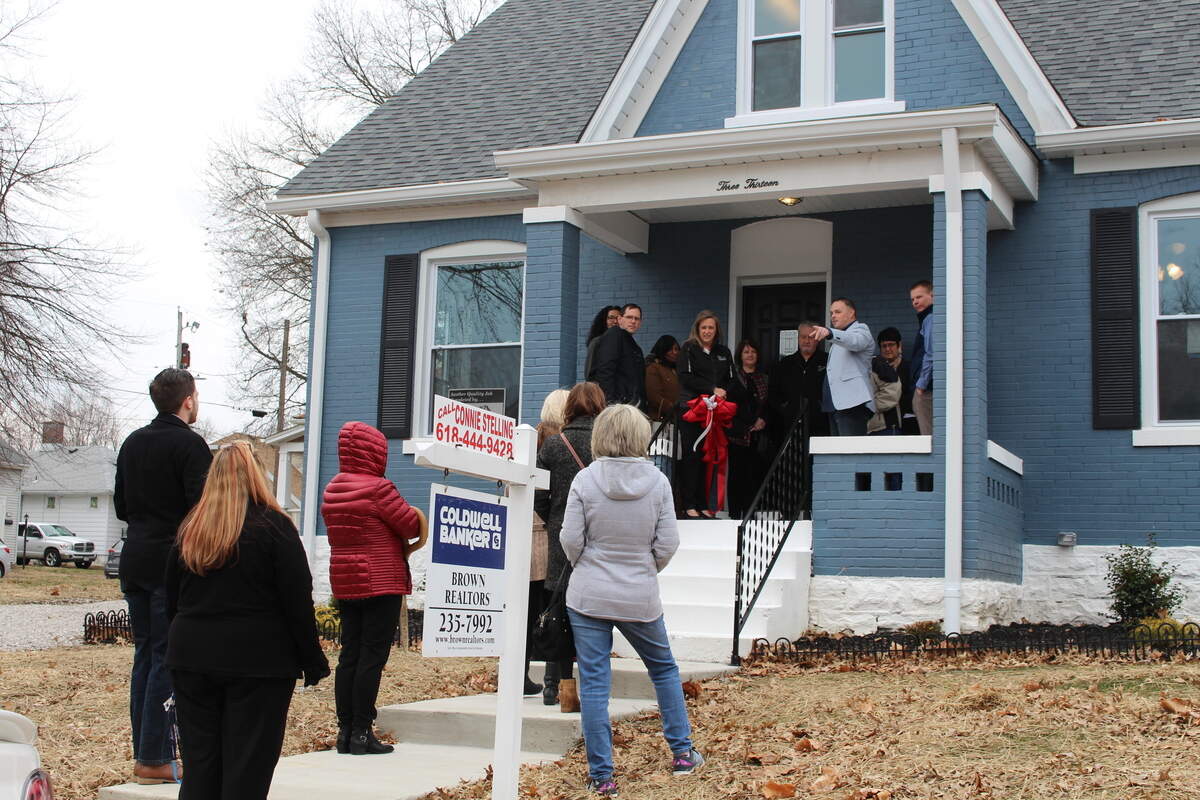 Belleville Community Development Corp. President Clint Forsythe, on porch in light jacket, addresses a small crowd at a ribbon-cutting and open house at 313 S. Ninth St. in Belleville on Tuesday.