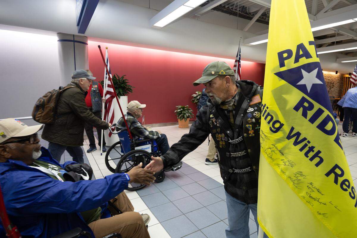 A member of the Patriot Riders greets a veteran as he moves in a parade through Lambert airport.