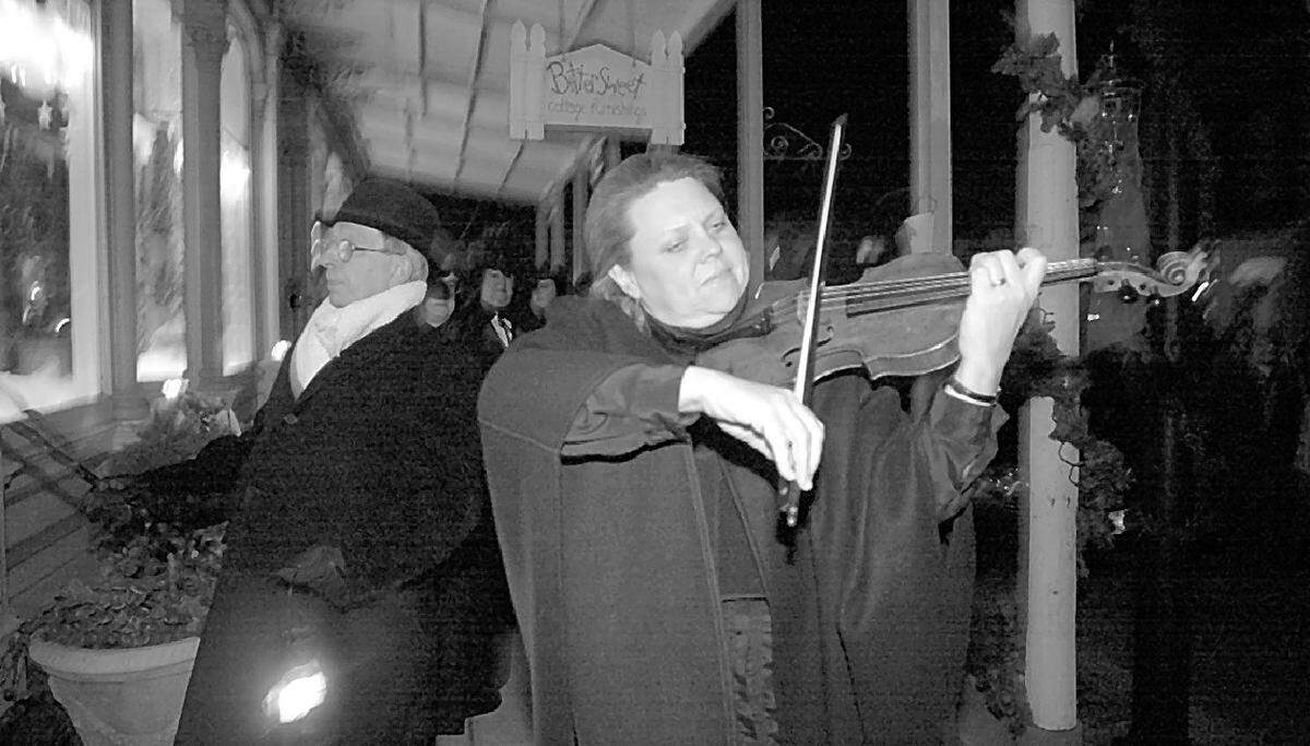 Night music: “Old Lamplighter” Dick Boyd, left, tapped on shop windows along West St. Louis Street in Lebanon as part of a previous Victorian Holiday Celebration. Darlene Lancer accompanied Boyd on violin. This year’s event takes place Friday, Nov. 22, and Saturday, Nov. 23.