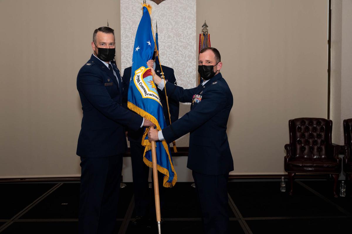 U.S. Air Force Col. Chris Robinson, 375th Air Mobility Wing Commander, receives the 375th Communications Group guidon from Col. Kyle Baldassari, 375th CG commander, during the 375th CG inactivation ceremony on Scott Air Force Base The passing of the guidon is a time-honored military tradition that signifies the transfer of responsibility for units and personnel.