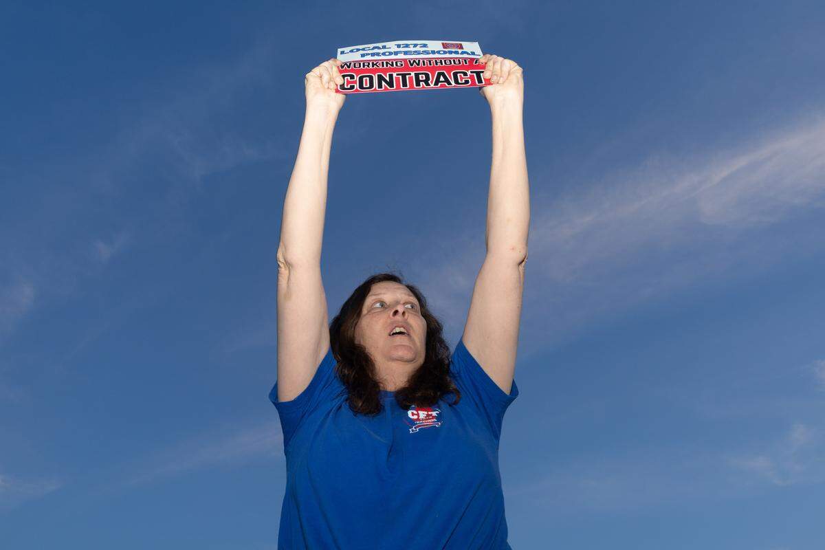 Heather Miller, a 7th grade social studies teacher, holds up a sign informing the community that despite it being weeks into the school year, she, along with other Cahokia Unit School District personnel, have been working without a current contract.