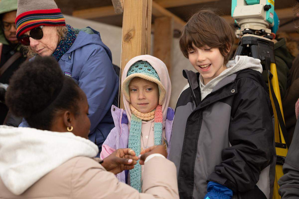 Principia student Natasha Kemirembe shows piece of a mastodon tooth to children at a paleontological dig site on campus. On Dec. 5, the day the tooth was finally removed from the ground, the school opened the site to the public.