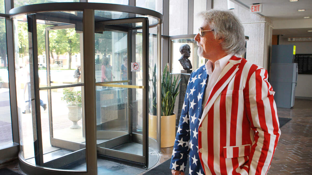 In this July 29, 2014, file photo, Bob Romanik waits on the first floor of the St. Clair County Building for county court in a red, white and blue Uncle Sam costume, minus the top hat, as a way of reminding the public, “If they can do this to me, they can do this to you.”