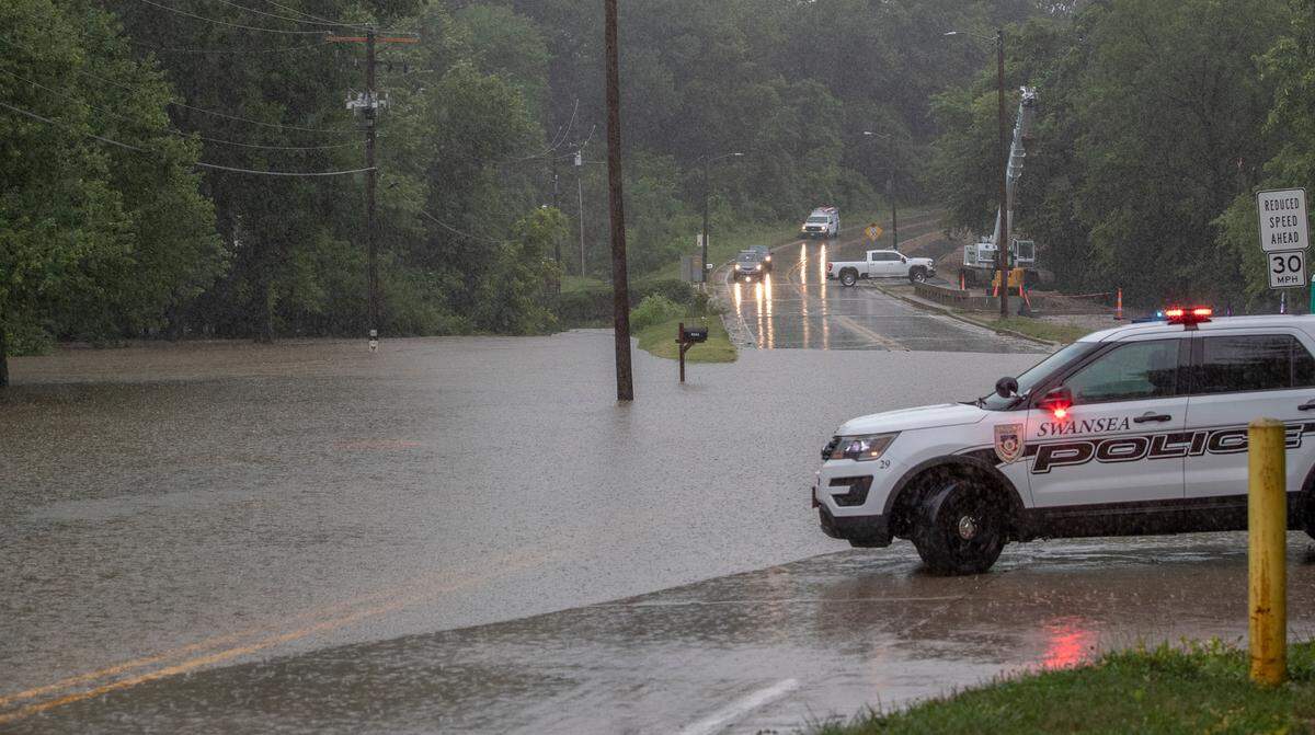 A Swansea police officer prepares to block traffic from continuing on Old Collinsville Ave. where Richland Creek had flooded the road Tuesday. Just two days later, St. Clair and Madison counties are again under a flash flood warning.