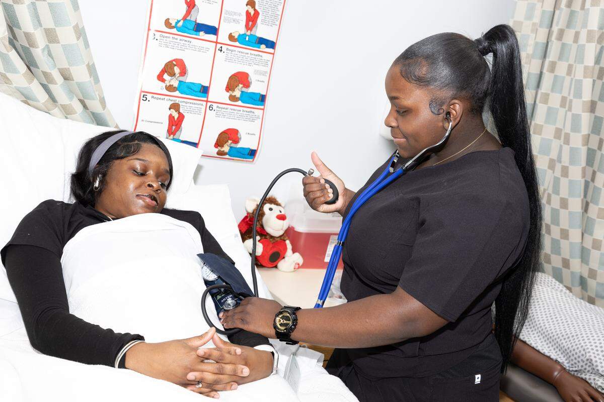 A student of East St. Louis High School’s certified nursing assistant program takes the blood pressure of a classmate.