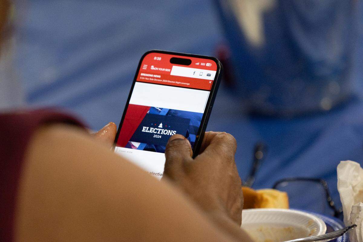 A supporter scrolls through their phone for coverage at LaToya Greenwood’s campaign watch party on Election Day, Nov. 5, 2024.