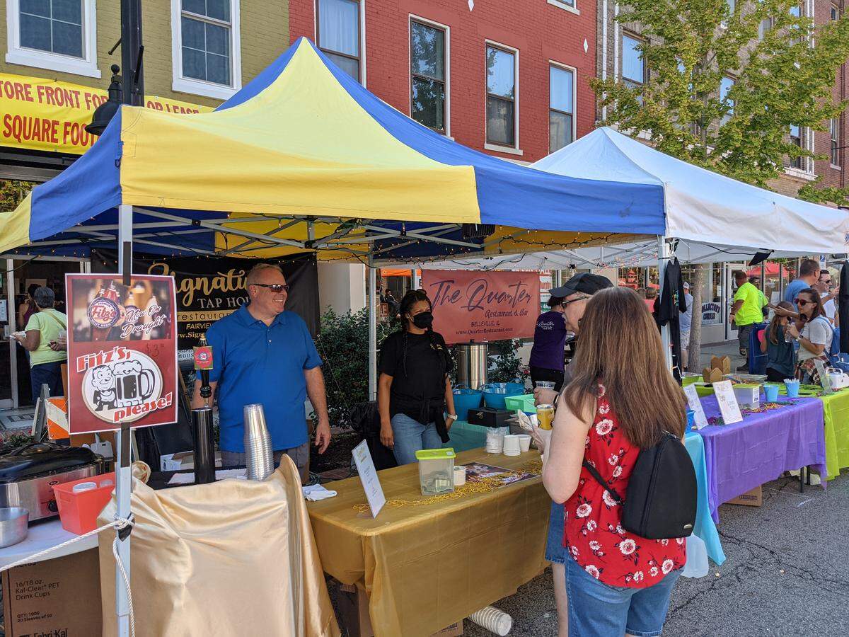 Brandon McGraw (wearing blue), owner of The Quarter Restaurant and Signature Tap House, chats with customers while working in their booth at the Belleville Chili Cook-Off in 2021.