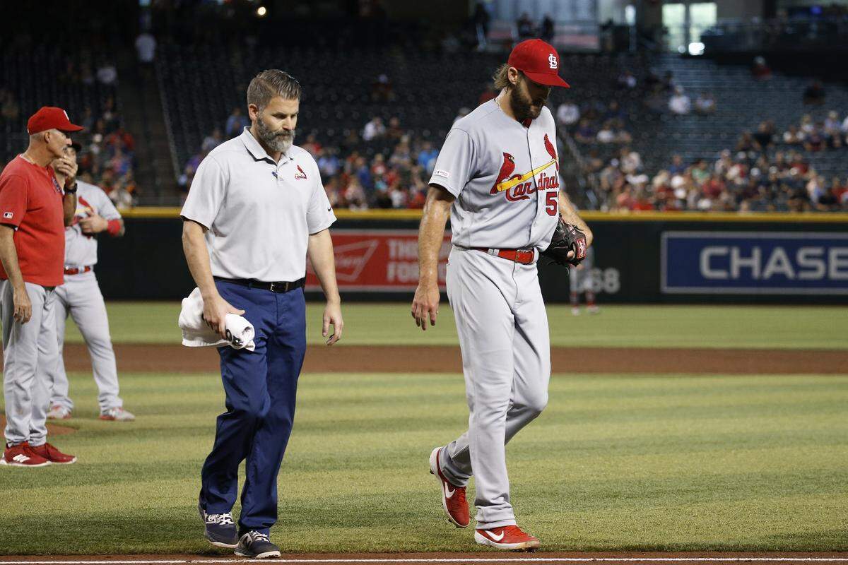 Injured St. Louis Cardinals starting pitcher Michael Wacha, right, walks off the field with head athletic trainer Adam Olsen, middle, as Cardinals pitching coach Mike Maddux, left, looks to the bullpen during the second inning of a baseball game against the Arizona Diamondbacks Wednesday, Sept. 25. The injury, a strained shoulder, will keep him off the Cardinals roster for the NLCS, which begins Friday. (AP Photo/Ross D. Franklin)