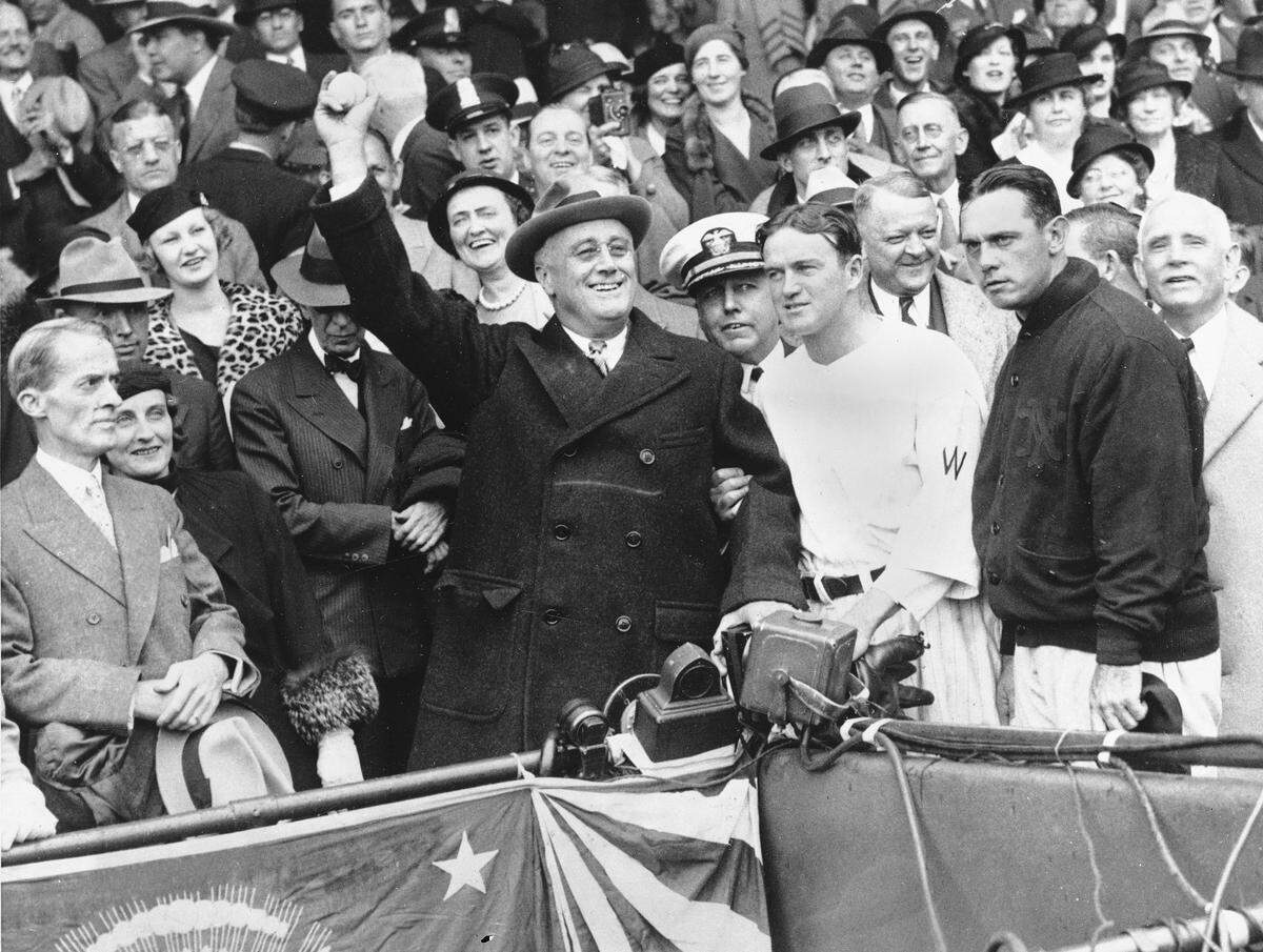President Franklin D. Roosevelt uncorked an almost wild throw that sent the players scrambling, Oct. 5, 1933, at the start of the third game of the World Series in Washington, D.C. Joe Cronin and Bill Terry, managers of the Senators and Giants respectively, are standing beside the Chief Executive. Terry has on the jacket. (AP Photo)