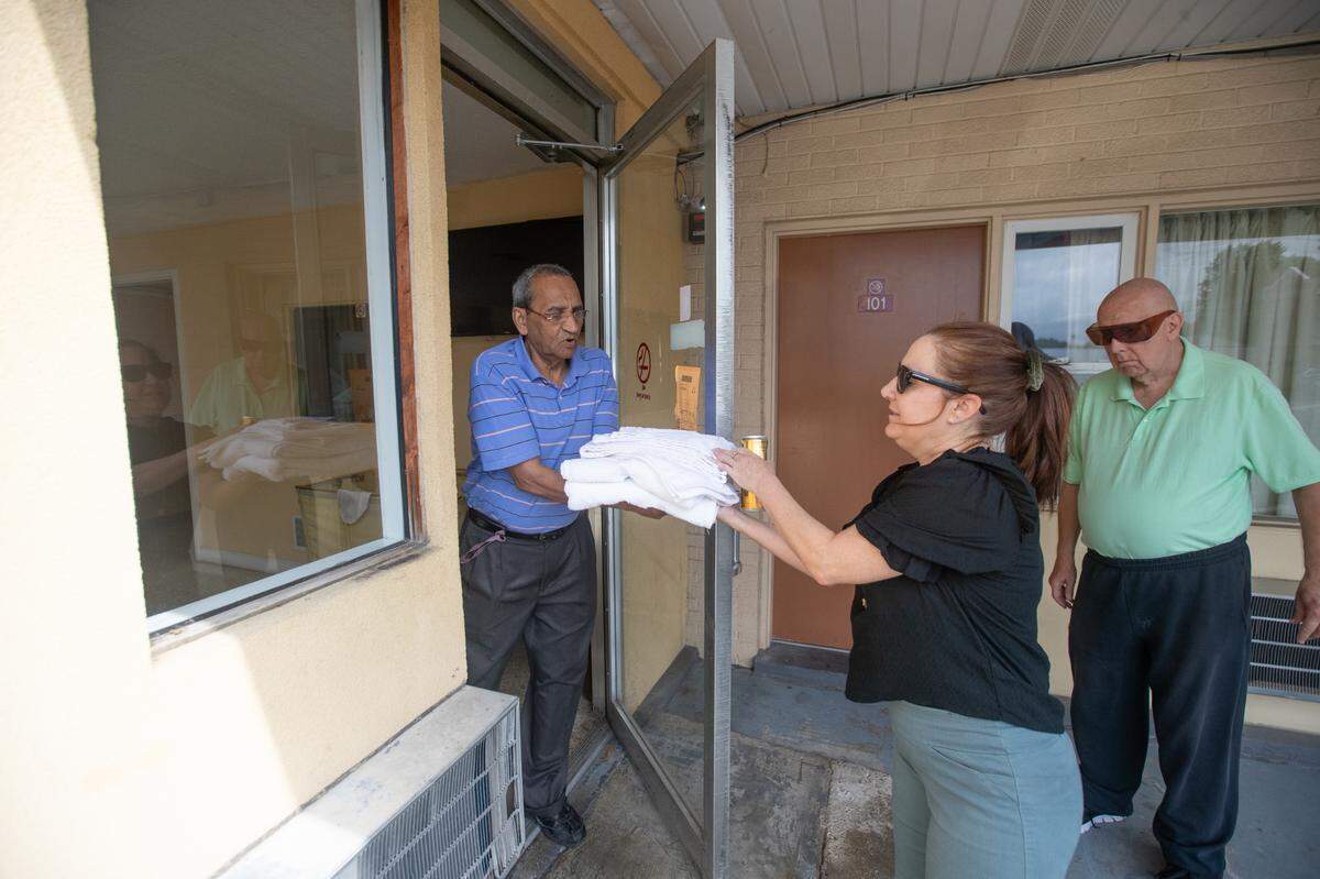 A manager of the Town House Motel in Belleville hands towels to Diane Burrelsman, a friend of guest David Semrau, right, who was evicted from his home. He’s very particular about cleanliness.