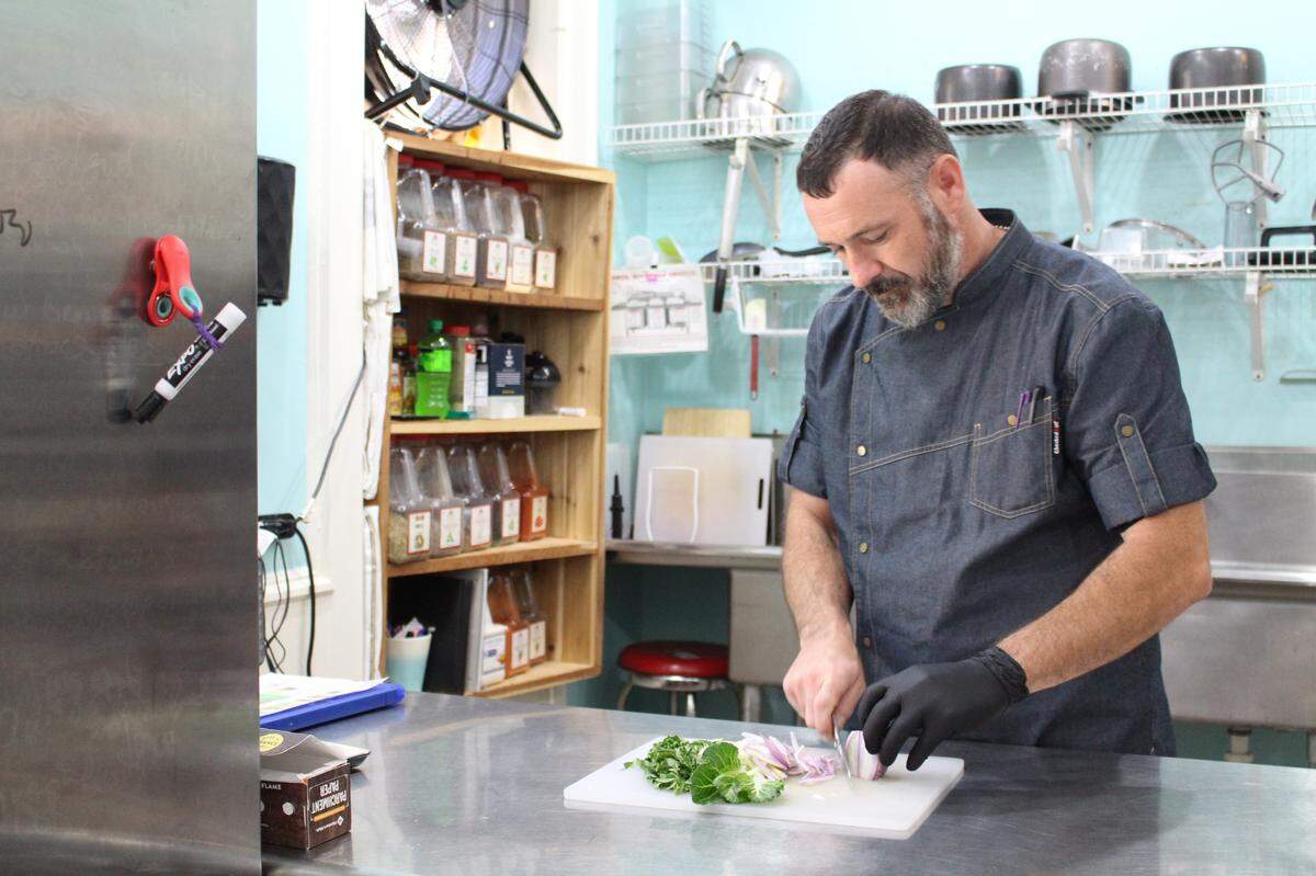 Chase Overacker cuts veggies for a bok-choy stir fry at Ruck Sack Meals in Highland. He honed his culinary skills as a Marine Corps cook and restaurant chef.