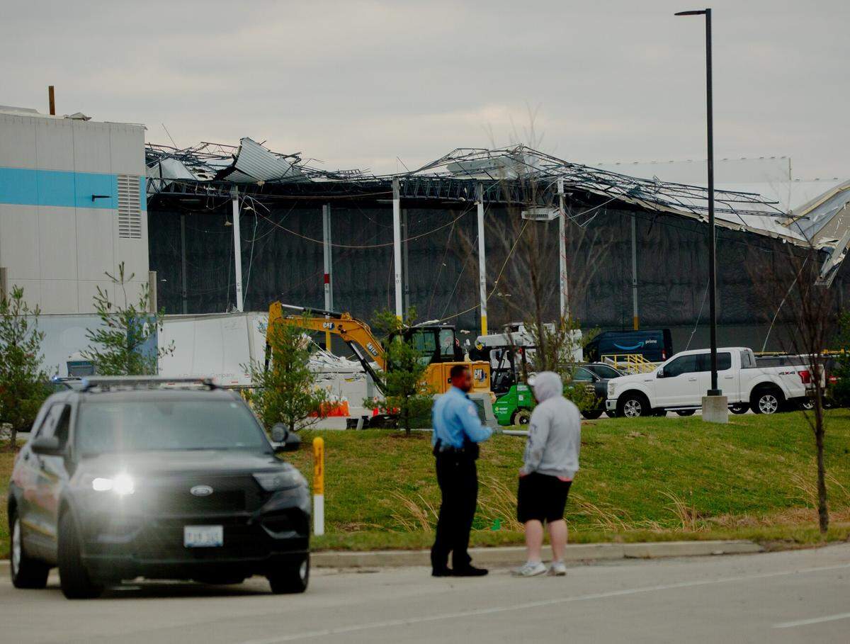 A police officer speaks to an onlooker at an Amazon Distribution Hub in Edwardsville last December. Six people died when a tornado hit the facility, and warehouses surrounding it could be just as vulnerable in the next major storm.