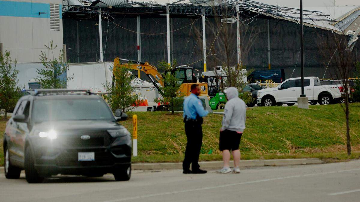 A police officer speaks to an onlooker at an Amazon Distribution Hub in Edwardsville last December. Six people died when a tornado hit the facility, and warehouses surrounding it could be just as vulnerable in the next major storm.