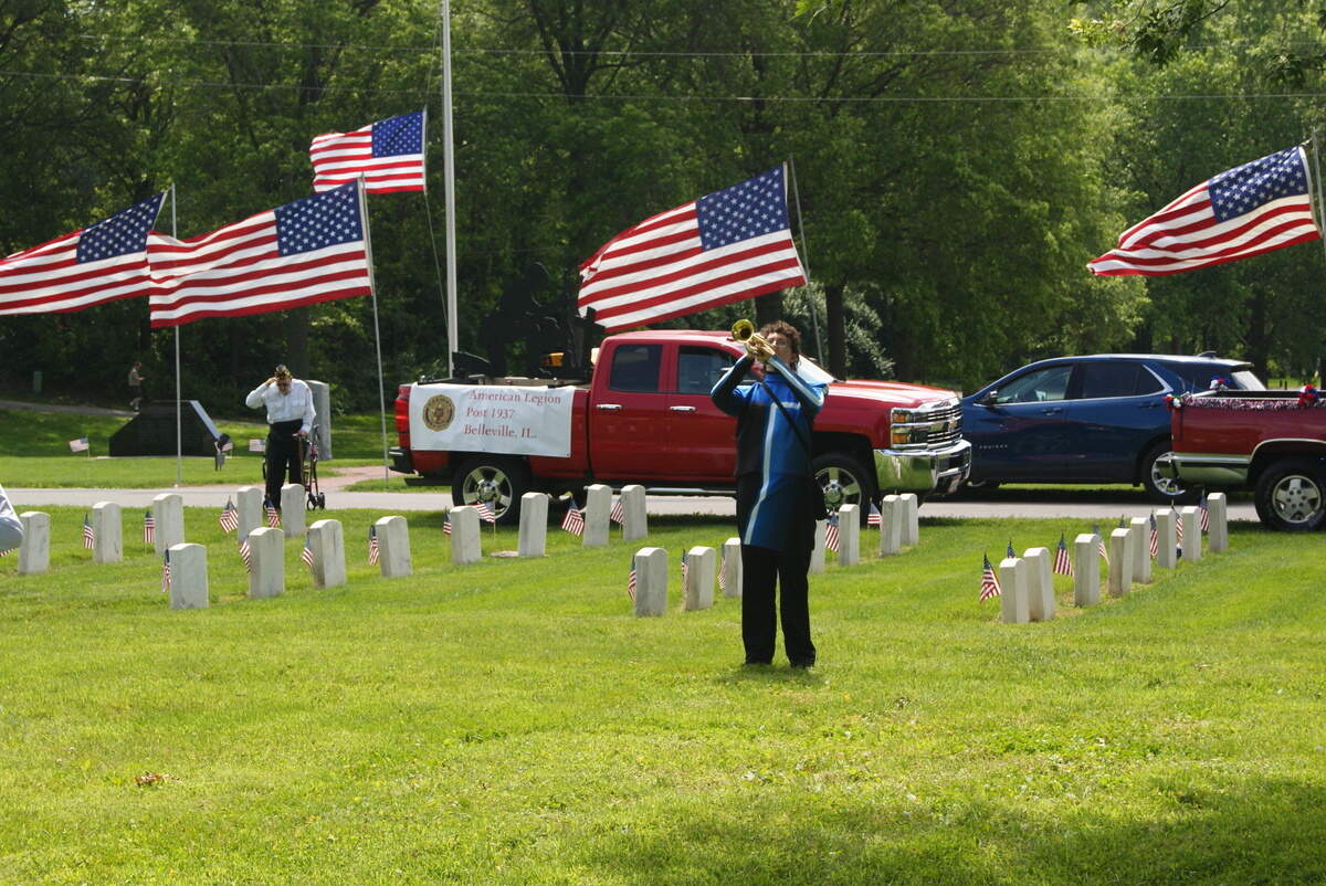 Quinn Peck, a rising senior at Belleville East High School, plays taps during the Belleville Memorial Day ceremony at Walnut Hill Cemetery at 1101 Mascoutah Ave. on Monday morning. In the background, Walter Sikora of American Legion Post 1937 in Belleville salutes during Peck’s performance. Sikora served in the U.S. Air Force.