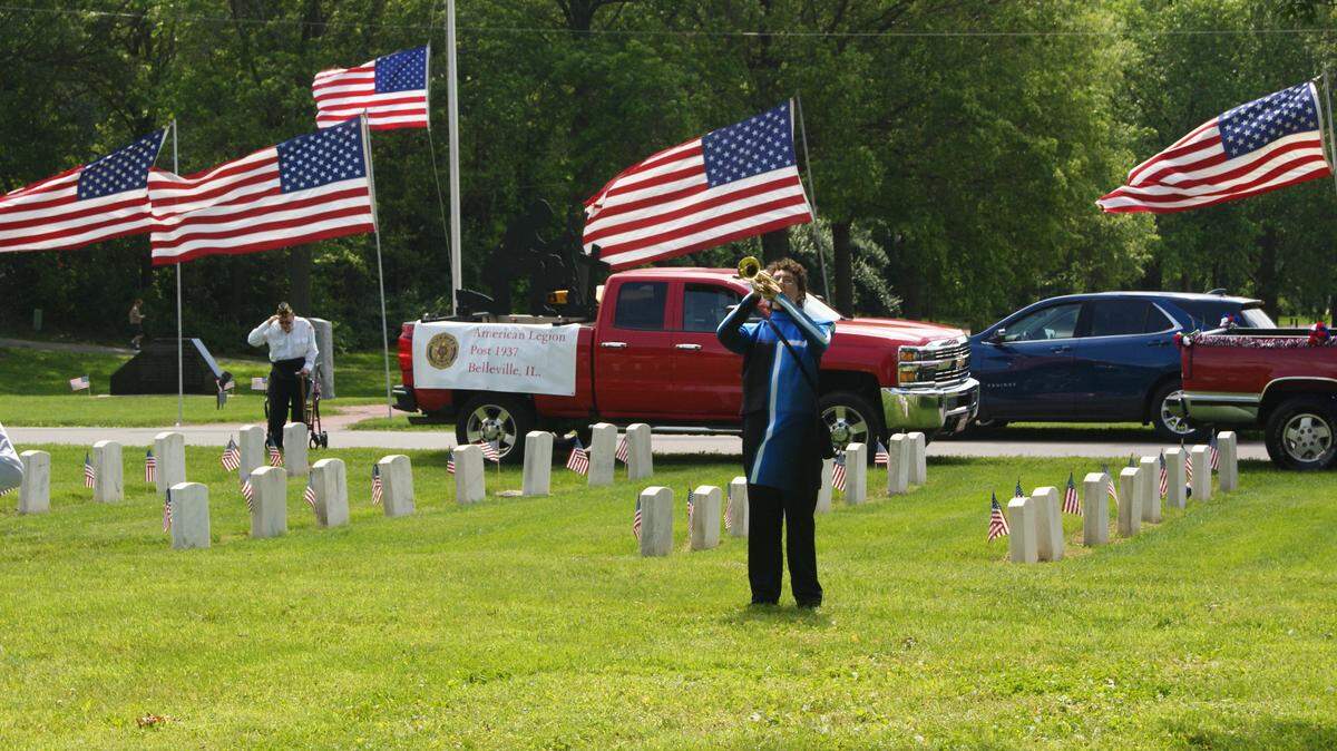 Quinn Peck of Belleville East High School plays taps last year during the Belleville Memorial Day ceremony at Walnut Hill Cemetery at 1101 Mascoutah Ave. In the background, Walter Sikora of American Legion Post 1937 in Belleville salutes during Peck’s performance. Sikora served in the U.S. Air Force.