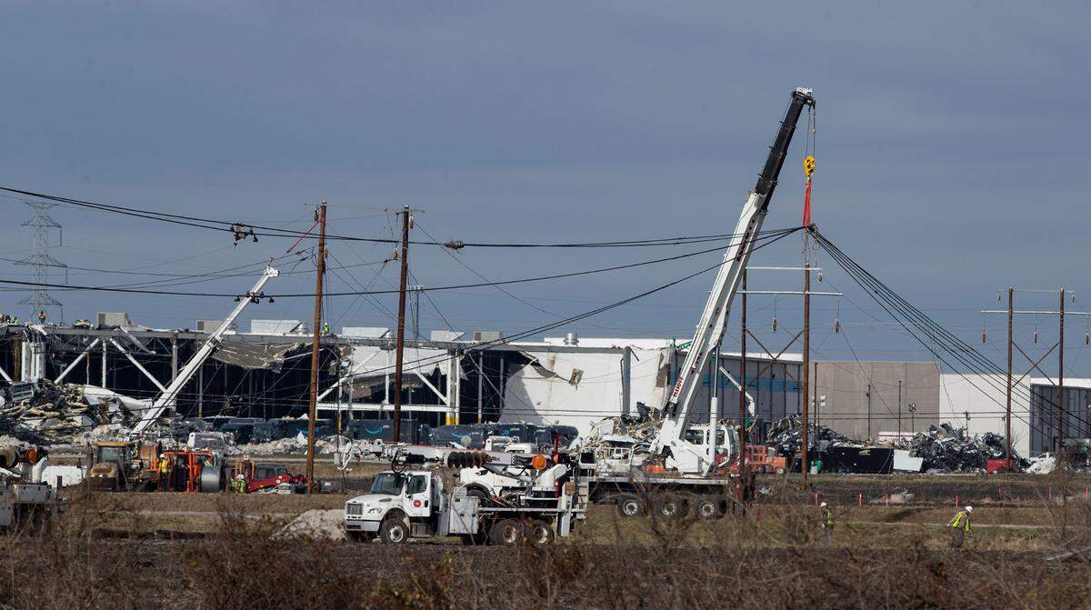 Utility crews work on repairing power line supports near the tornado damaged Amazon warehouse in Edwardsville, Illinois.