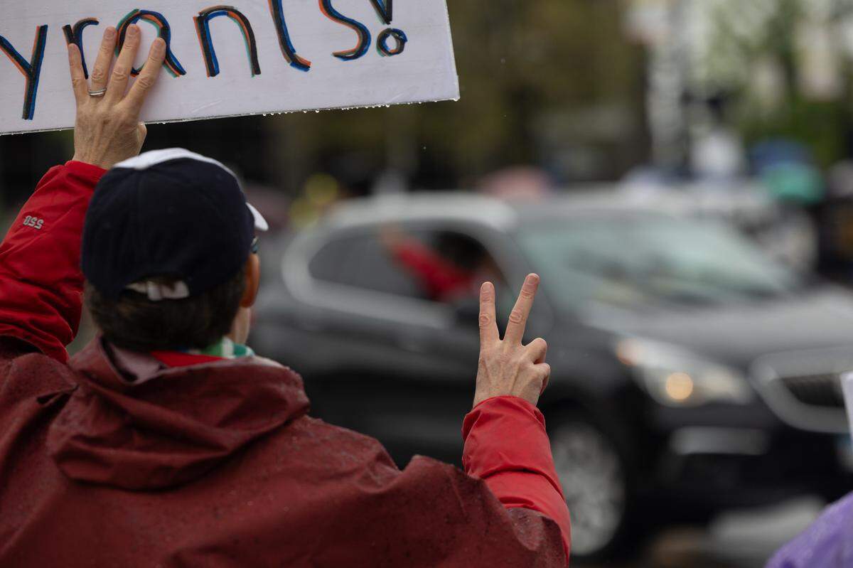 A protester holds up a peace sign at a supportive motorist as they pass Belleville’s Public Square.