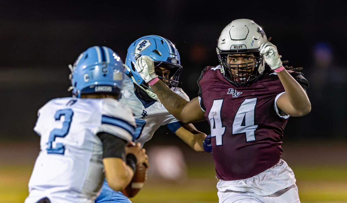 Belleville West’s Jeremiah Ward puts pressure Belleville East quarterback Kayden Wood Friday at Goalby Field.