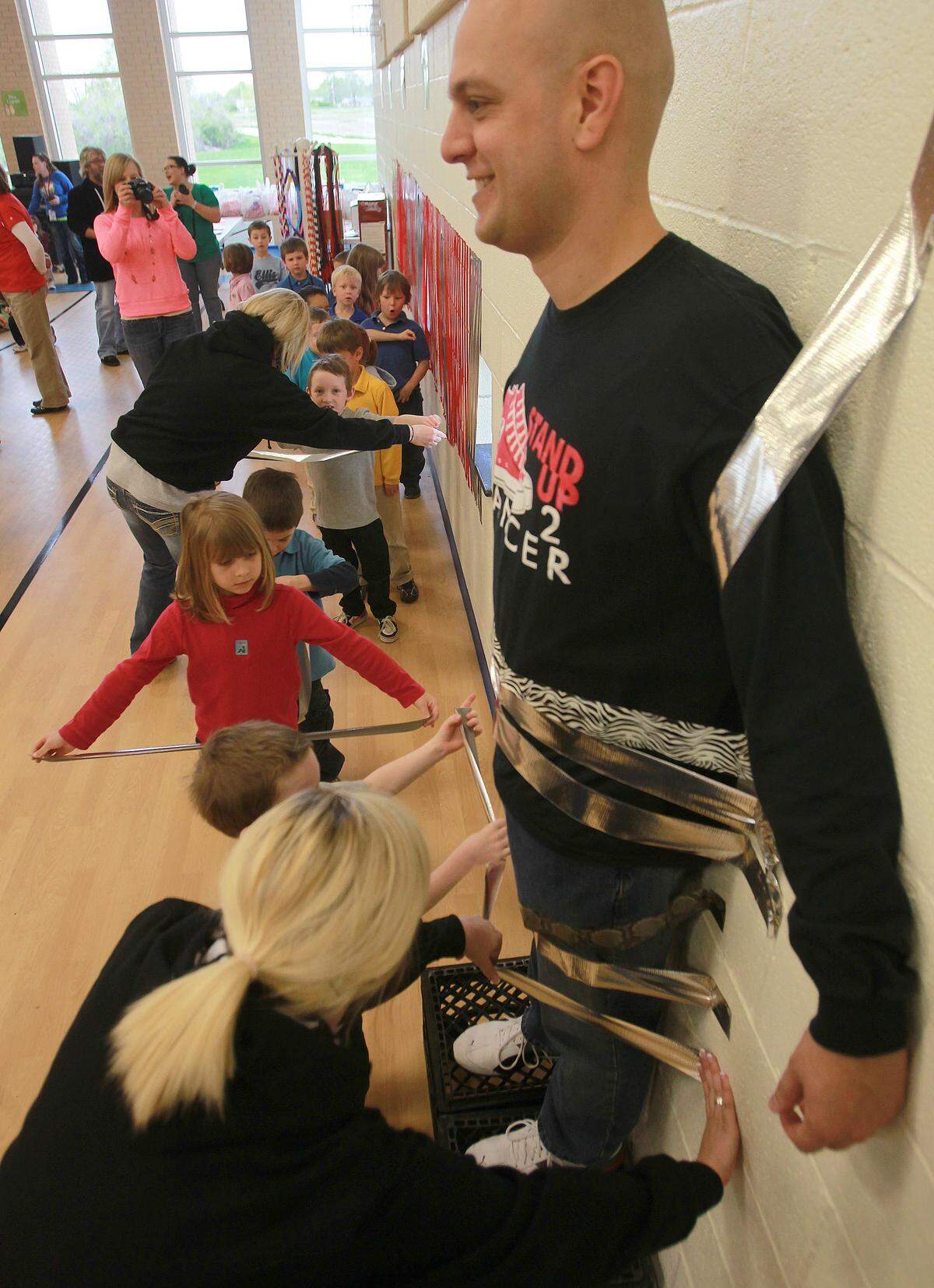 When he was the principal at Ellis Elementary School, Dave Deets made a deal with the student body that he would allow himself to be taped to the wall of the gym if the students reached their $2,500 goal for a fundraiser for the American Heart Association. Deets had to pay up during an all-school assembly on April 19, 2013, when the elementary school students brought in $8,849. In this file 2013 photo, teachers help the younger students apply the tape around Deets, securing him to the wall.