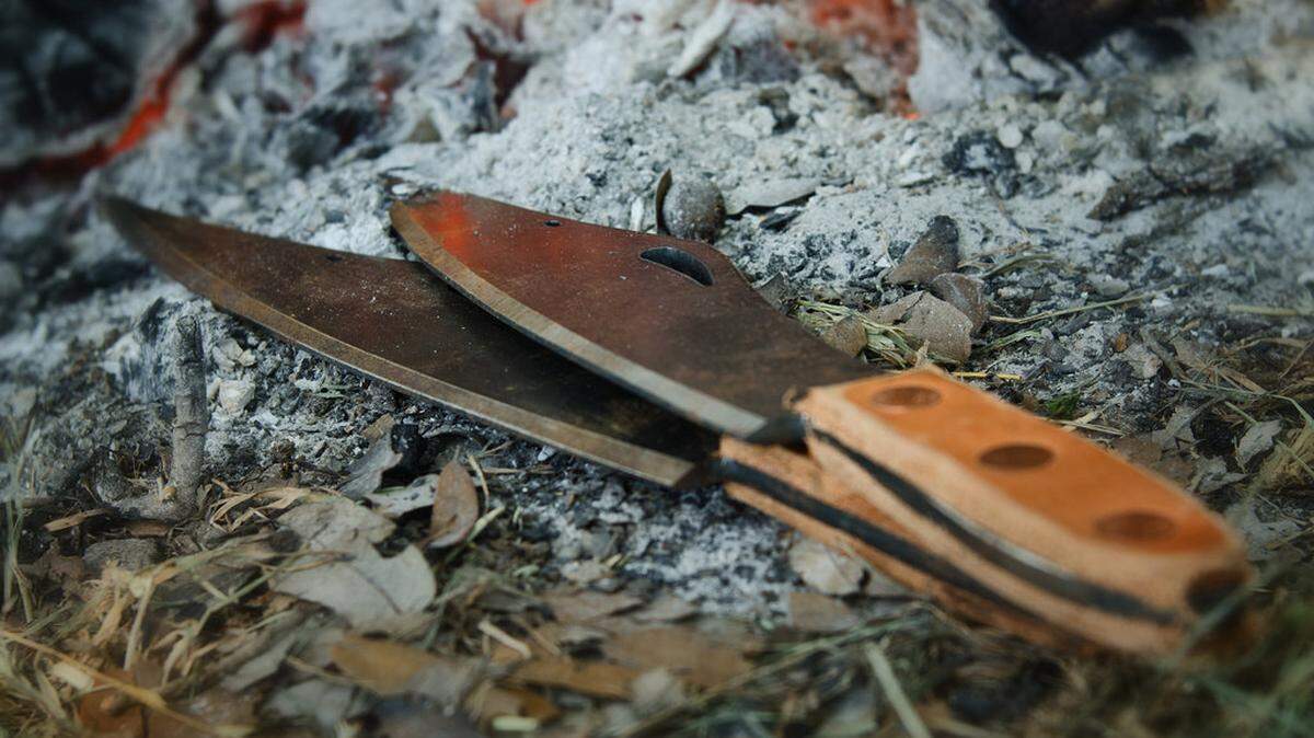 A pair of throwing knives near a fire.