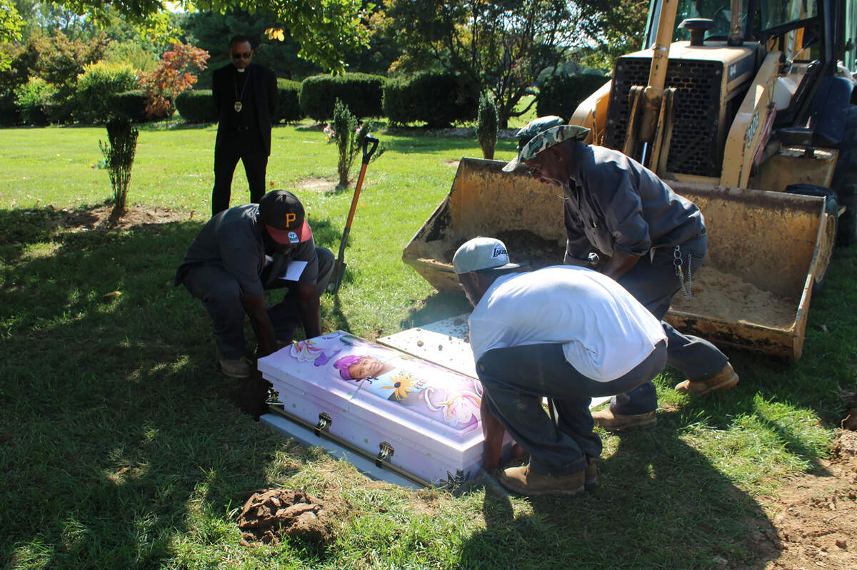 Cemetery workers lower Calyia Stringer’s casket into the ground after the 3-year-old was killed by a stray bullet last year. Her casket featured a custom wrap designed by a local funeral home and Damian Ferek’s company, CasketWraps.