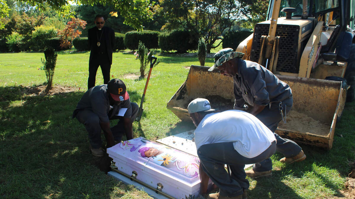 Cemetery workers lower Calyia Stringer’s casket into the ground after the 3-year-old was killed by a stray bullet last year. Her casket featured a custom wrap designed by a local funeral home and Damian Ferek’s company, CasketWraps.
