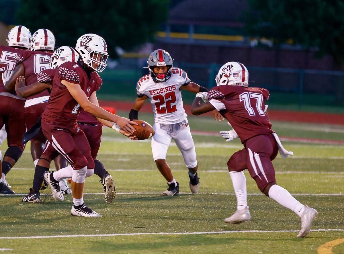 Belleville West’s Landon McDonald hands off the ball to Kyle Hughes against Alton in a Southwestern Conference game Friday, Sept. 16. The Maroons ultimately lost 28-7.