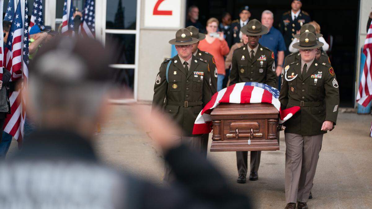 A member of the Patriot Guard salutes a procession at Lambert airport on Oct. 24, 2023 for the homecoming of Cpl. James A. Hurts, who died in World War II during the Bataan Death March.