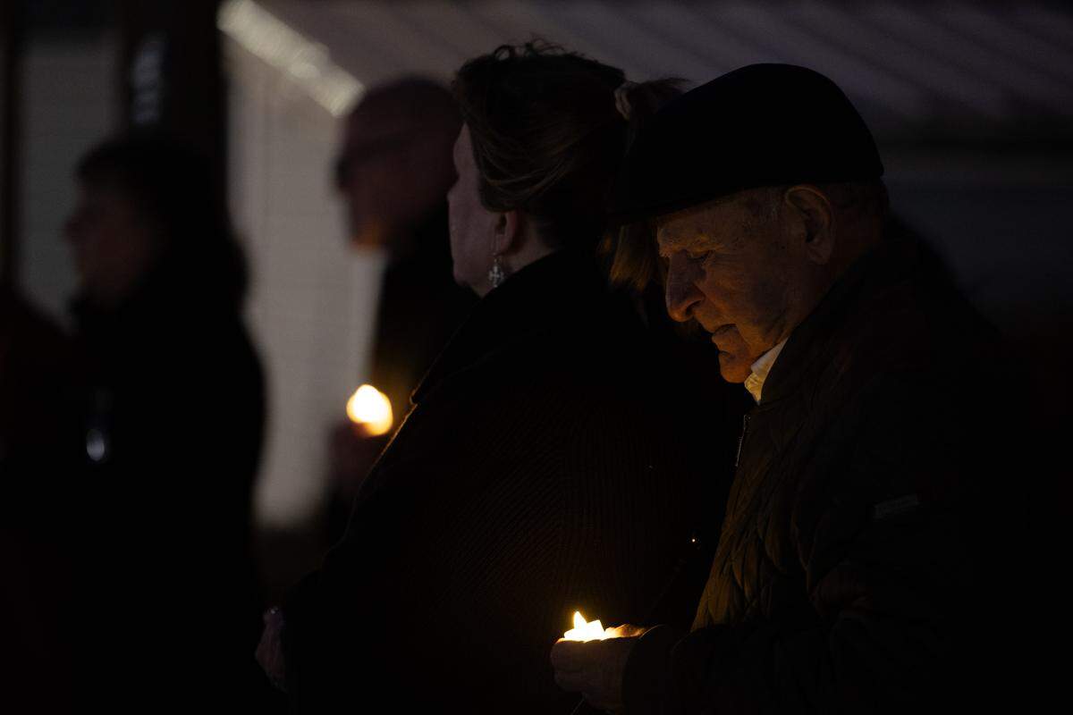 Mourners hold electric candles during a candlelight vigil prior to the tree lighting ceremony.