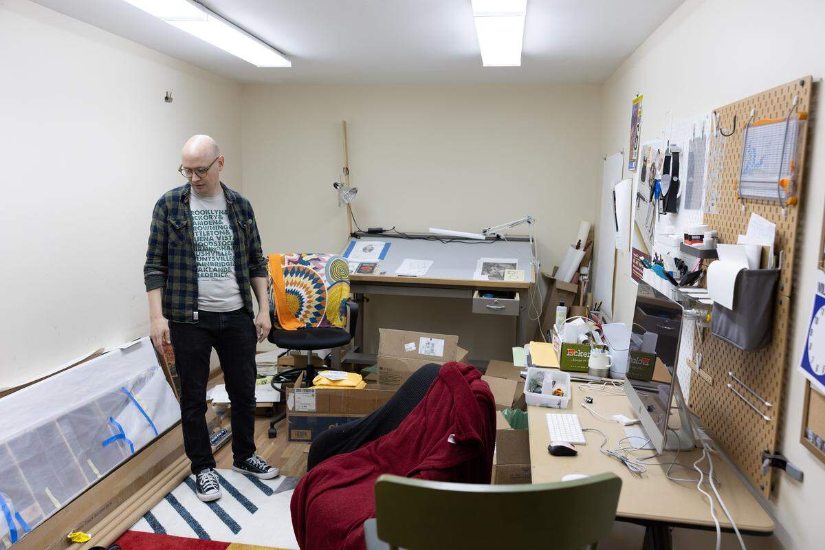 Danny Houk stands in a multi-purpose workshop and storage space, where hundreds of zines and other art mediums are kept.