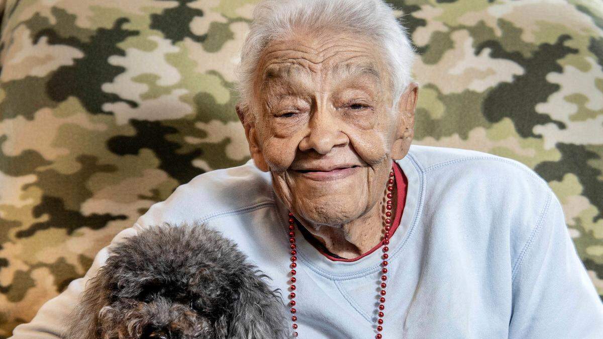In this Sept. 4 photo, former educator Teretha Johnson poses with her 14-year-old poodle Satchel, at her home in Savoy, Ill. Johnson was Champaign’s first African-American teacher.