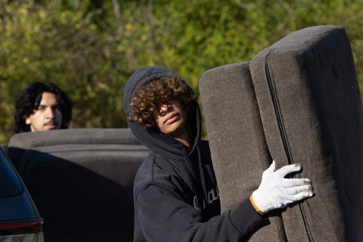 Volunteers bring abandoned and dumped furniture to a dumpster at a cleanup in East St. Louis on Nov. 15, 2024.