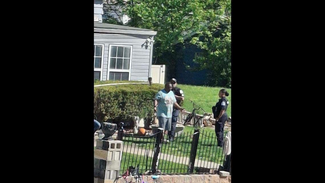 George Green talks to Belleville police officers on Wednesday while sanitation workers and tow trucks remove trash and vehicles from his properties on South 19th Street.