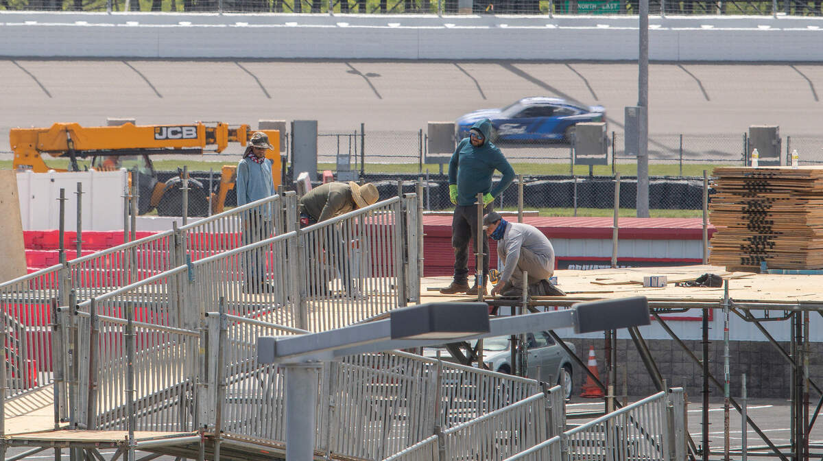 Workers assemble a temporary hospitality structure at World Wide Technology Raceway in preparation for the inaugural NASCAR Cup Series race — the Enjoy Illinois 300 — on Sunday, June 5. In the background, Ford driver David Ragan runs test laps on the track. Illinois Gov. J.B. Pritzker is excited about the marquee event, citing the potential economic boon it could create for the metro-east region and the entire state.