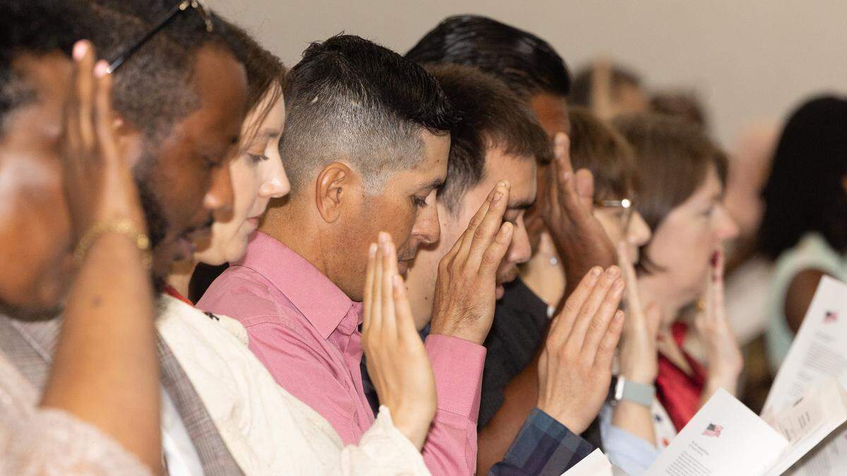 New citizens of the United States raise their hands to swear oaths of allegiance during a naturalization ceremony in Collinsville.
